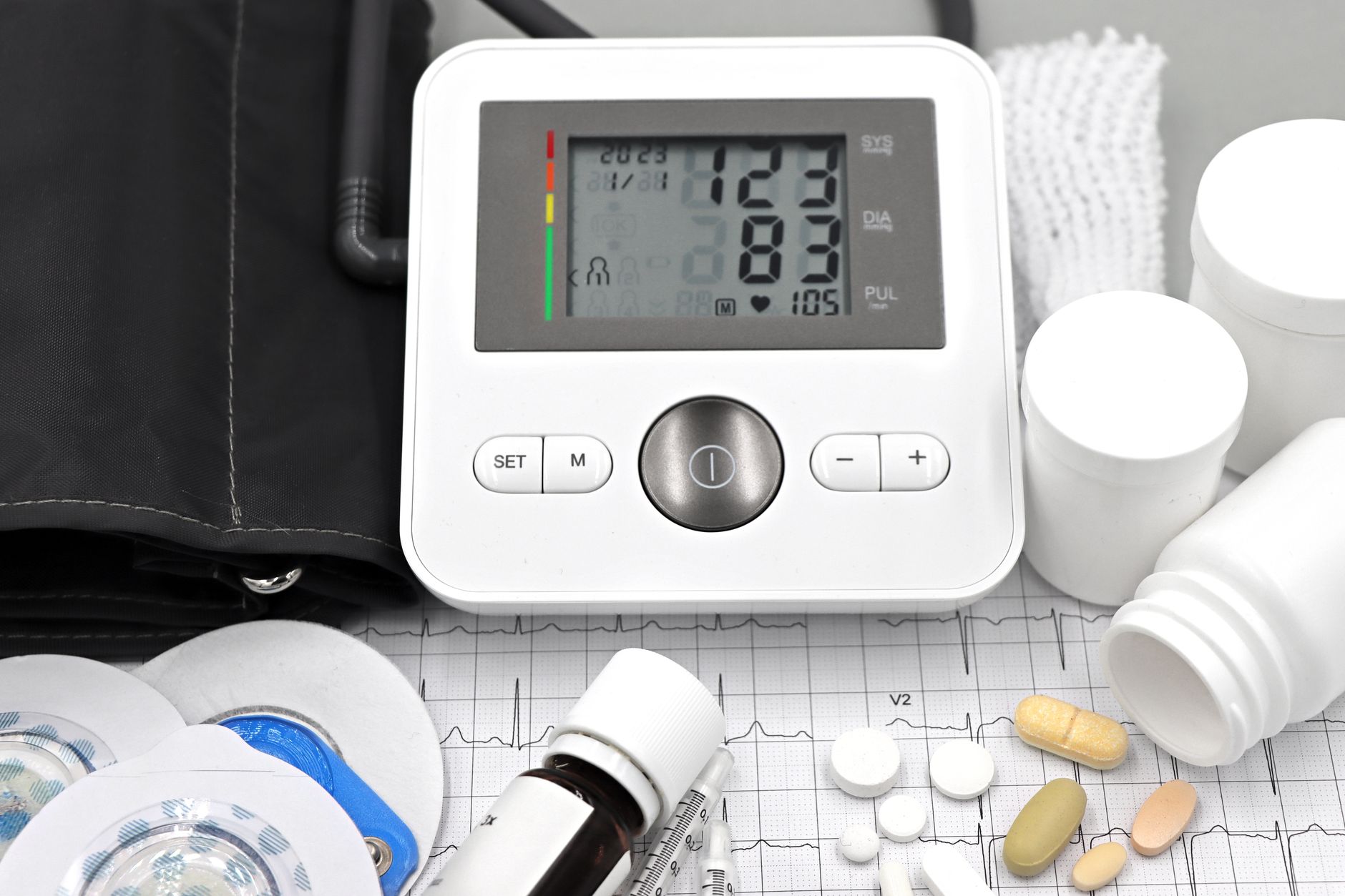 Close-up of medical equipment including blood pressure monitor, pills, and ECG printout. (Photo by Marta Branco on Pexels)